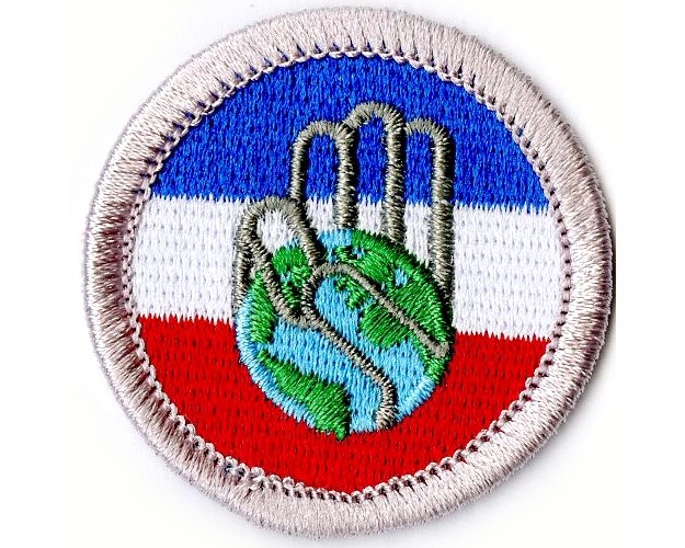 The Citizenship in Society emblem, a hand doing the Scout sign with the world as the palm of the hand