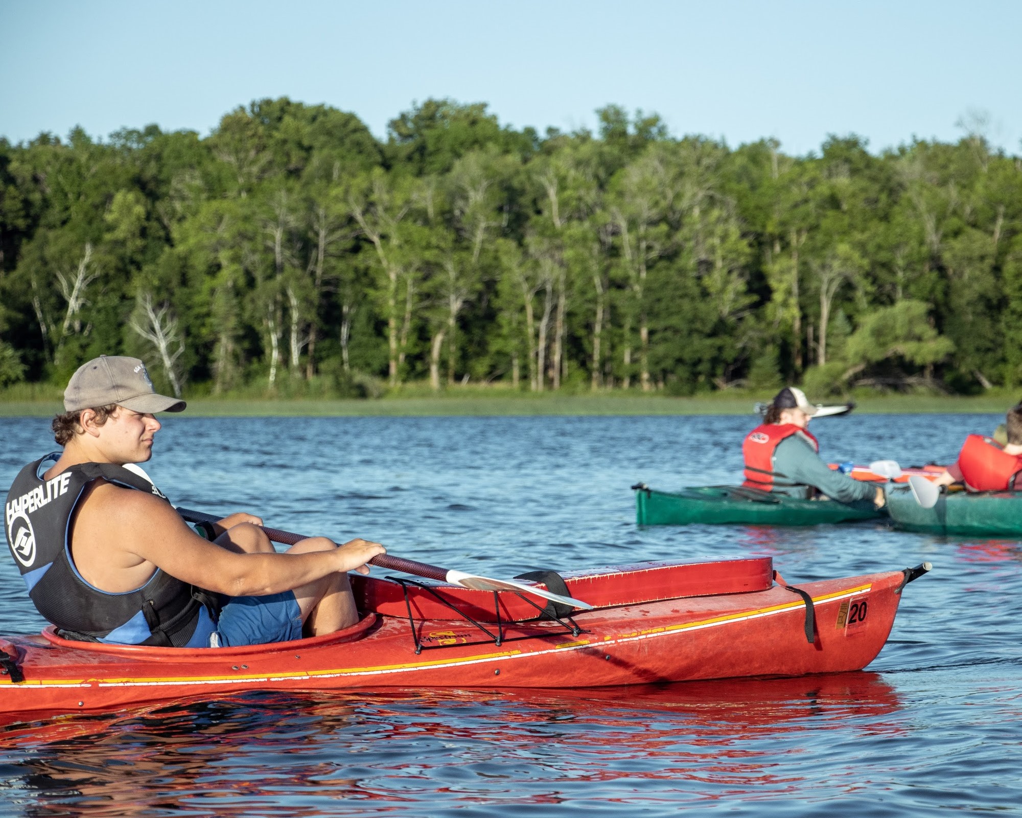 Three Scouts in life jackets are floating in the lake taking a break from kayaking