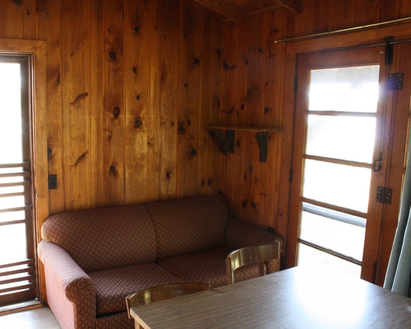 Picture of the cabin living room, showing a couch and small dining table with lots of natural light