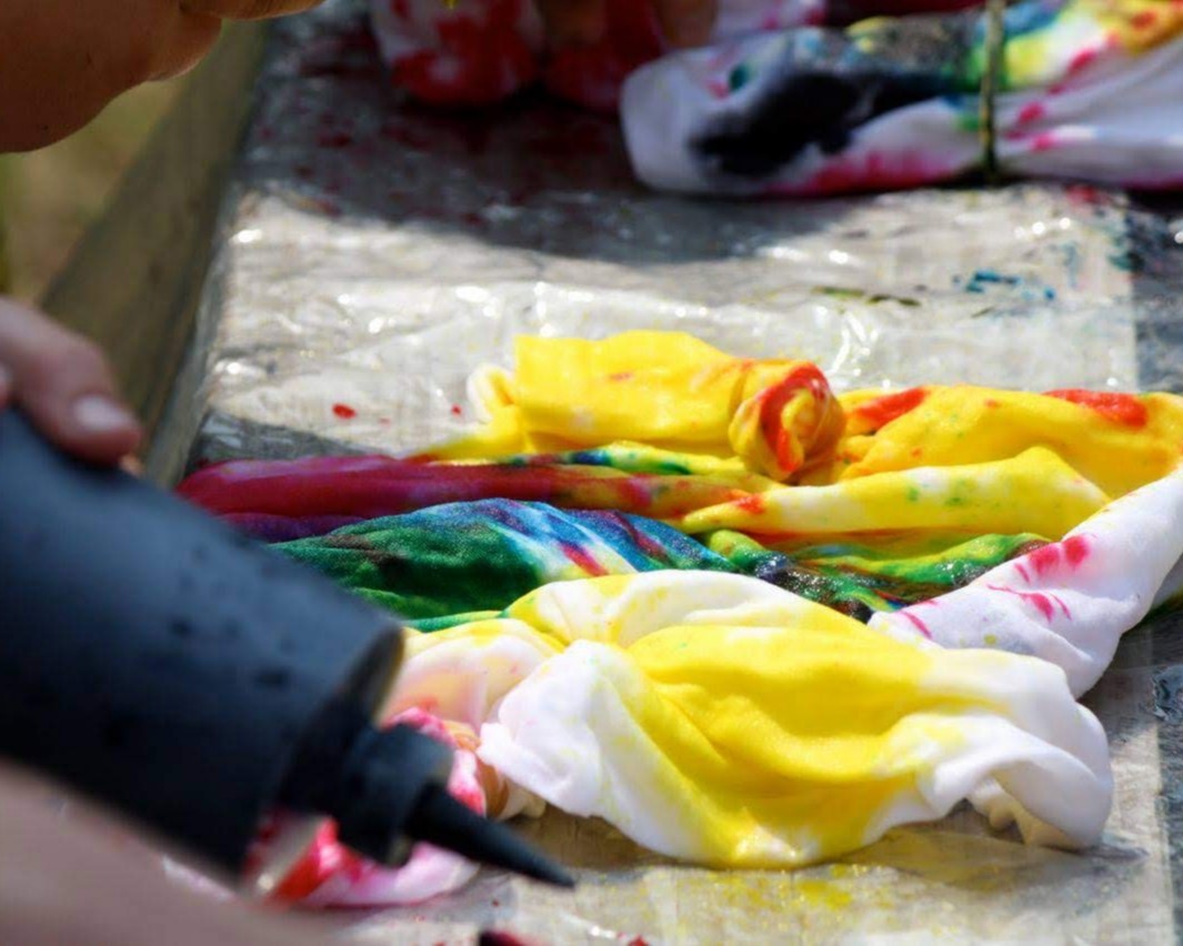 A bottle of dye for tie-dye and a pile of items in the middle of being dyed