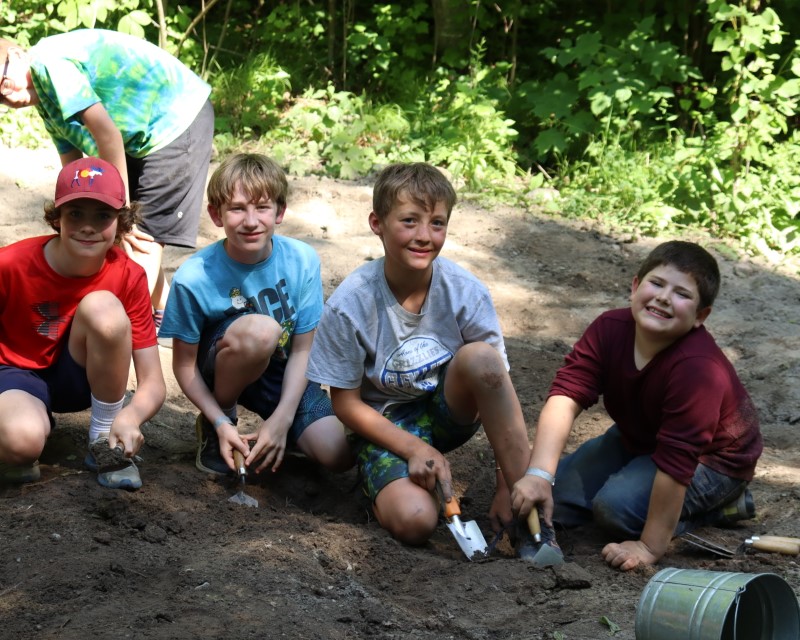 Four Scouts holding trowels and digging