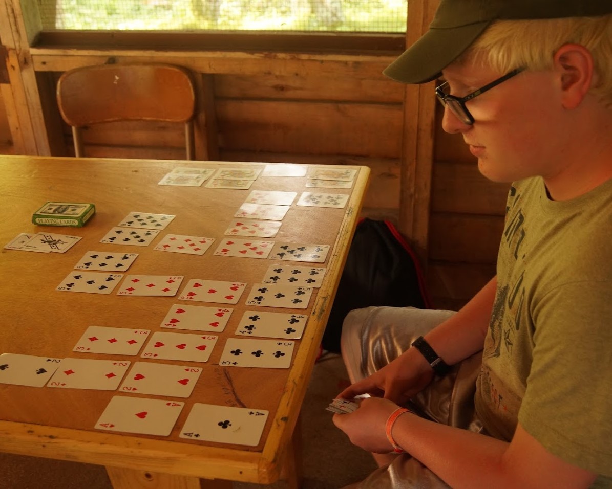 A Scout dealing a set of playing cards onto a table