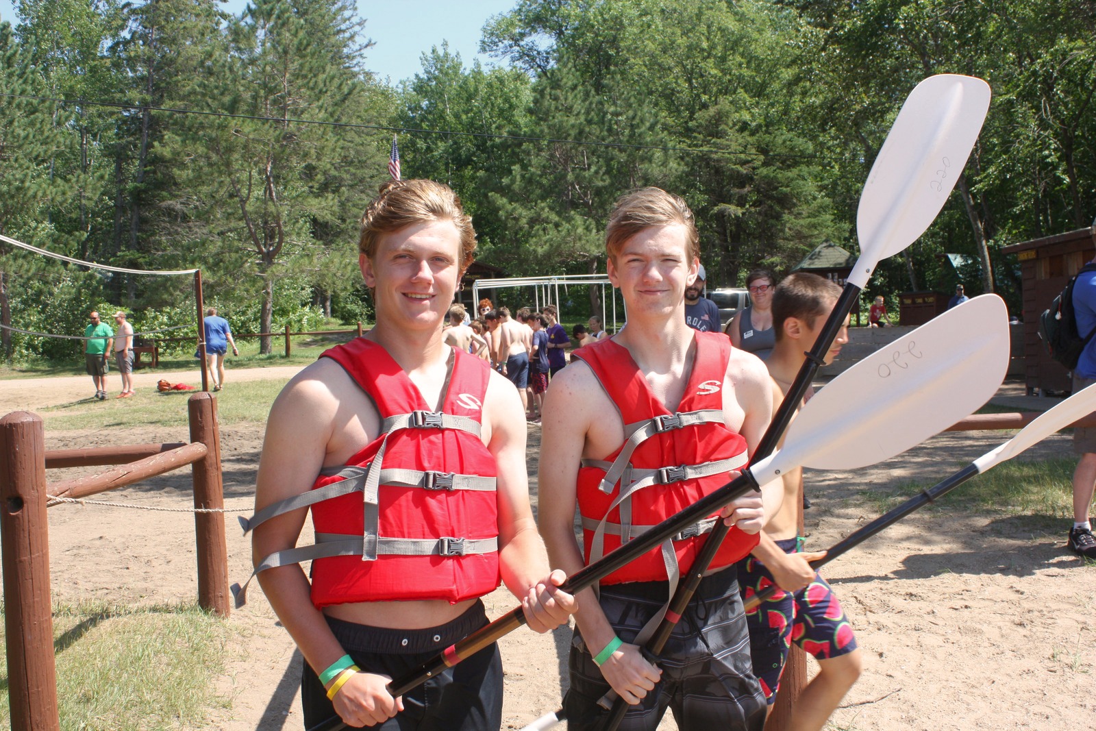 Two Scouts posing on the beach with PFD's and kayak paddles.