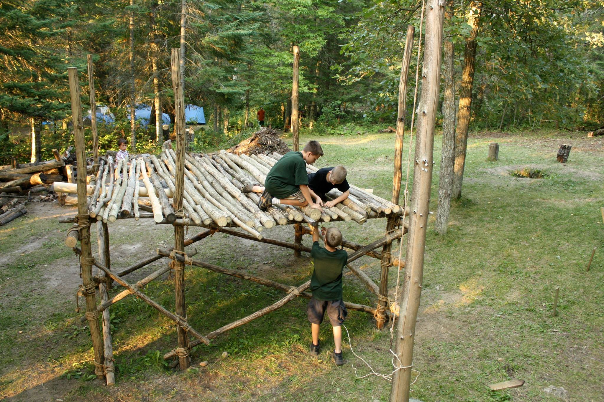 Several scouts working on lashing poles to the floor of a pioneering structure.